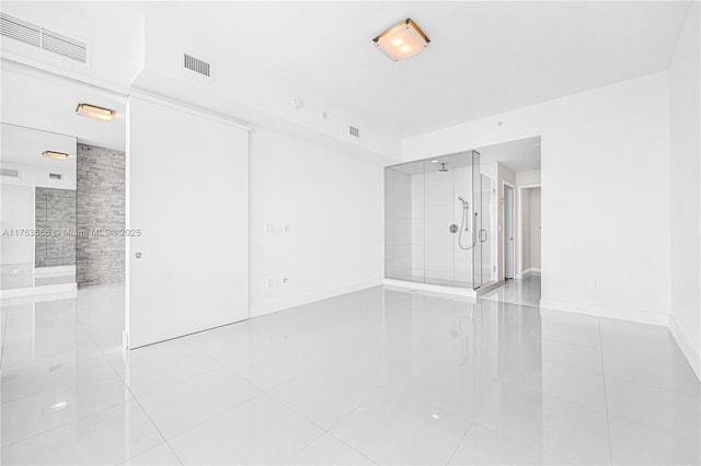 unfurnished bedroom with visible vents, baseboards, connected bathroom, and light tile patterned floors