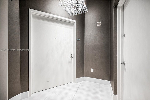 interior space featuring tile patterned floors, baseboards, and an inviting chandelier