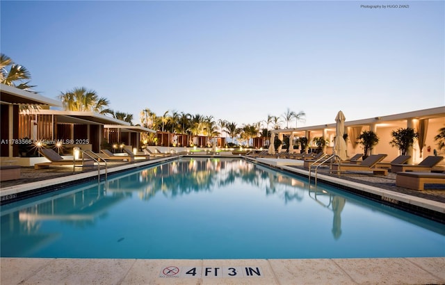 pool at dusk with a patio area and a community pool