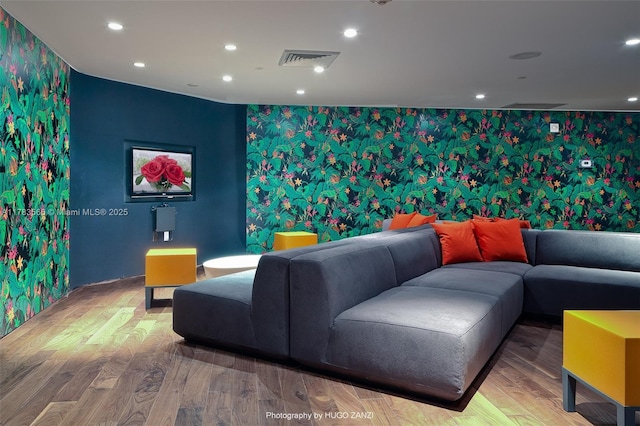 home theater with visible vents, an accent wall, wood finished floors, and wallpapered walls