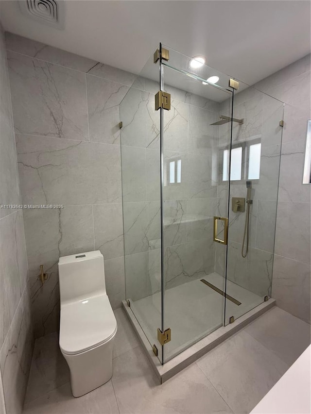bathroom featuring visible vents, toilet, tile walls, a shower stall, and tile patterned flooring