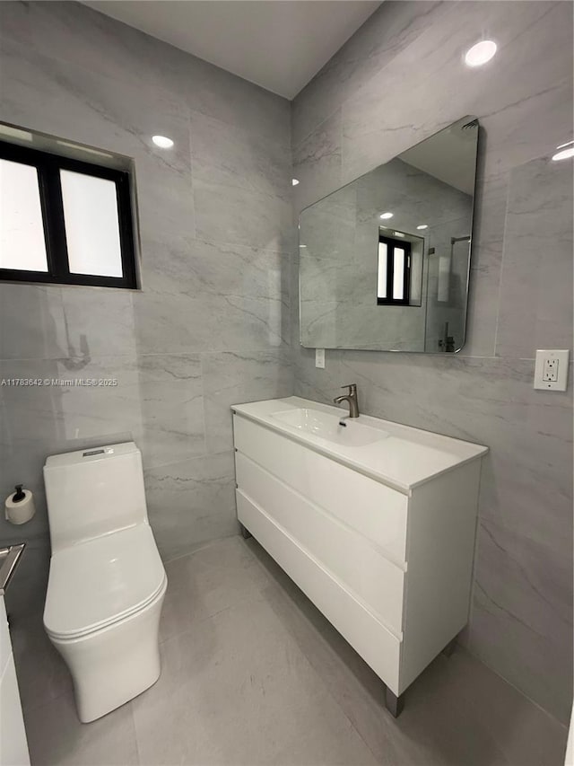 bathroom featuring toilet, vanity, and tile walls