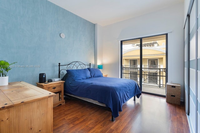 bedroom featuring access to exterior, multiple windows, and wood finished floors