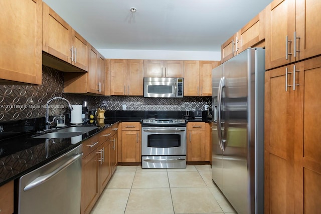 kitchen with appliances with stainless steel finishes, light tile patterned floors, brown cabinetry, decorative backsplash, and a sink