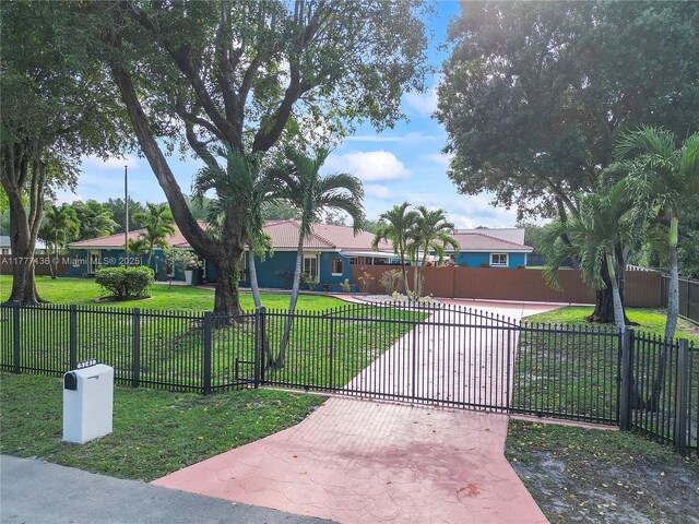 ranch-style home featuring a gate, fence private yard, a front lawn, and driveway