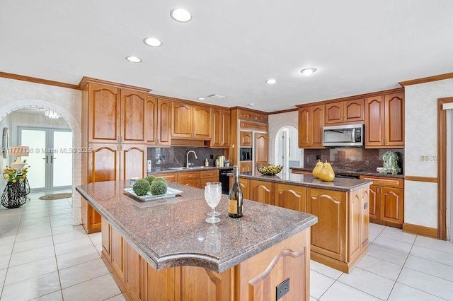 kitchen with recessed lighting, arched walkways, stainless steel microwave, a large island, and crown molding
