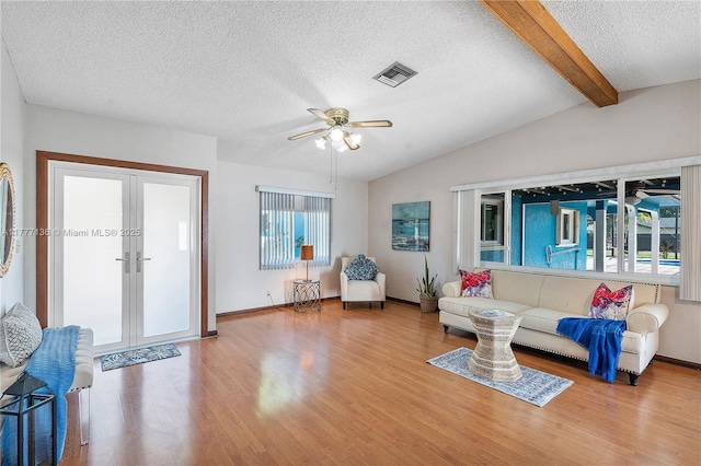 living room featuring a textured ceiling, visible vents, a ceiling fan, and wood finished floors