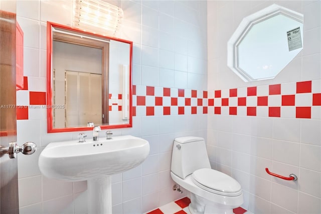 bathroom featuring tile walls and toilet