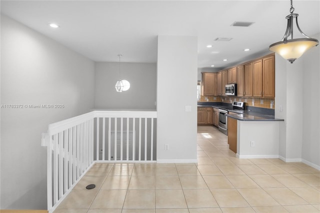 922 NW 127th Ave, Coral Springs, FL 33071 - kitchen featuring stainless steel appliances, dark countertops, light tile patterned floors, brown cabinetry, and recessed lighting