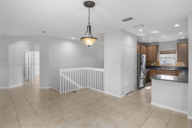 922 NW 127th Ave, Coral Springs, FL 33071 - kitchen with arched walkways, stainless steel fridge with ice dispenser, dark countertops, recessed lighting, and light tile patterned flooring