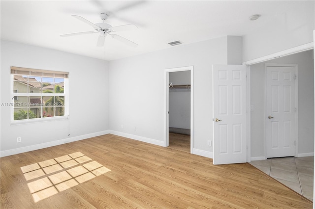 922 NW 127th Ave, Coral Springs, FL 33071 - unfurnished bedroom featuring light wood-style floors, a closet, a ceiling fan, and a walk in closet