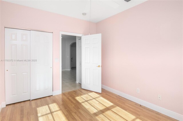 922 NW 127th Ave, Coral Springs, FL 33071 - unfurnished bedroom with arched walkways, light wood finished floors, and a closet