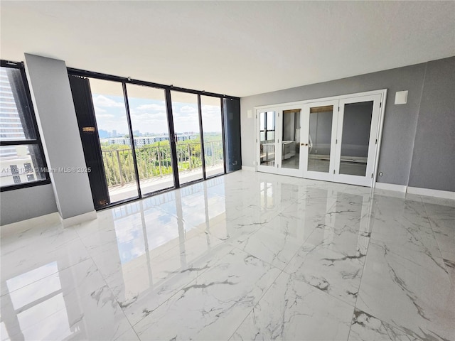 empty room featuring french doors, baseboards, marble finish floor, and expansive windows