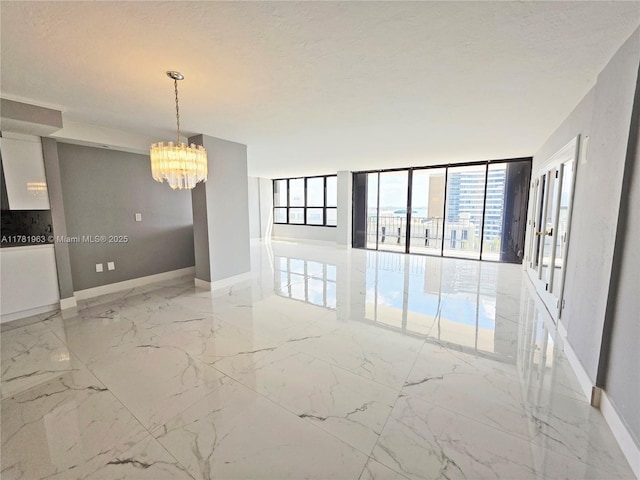 unfurnished room featuring baseboards, marble finish floor, a notable chandelier, and floor to ceiling windows
