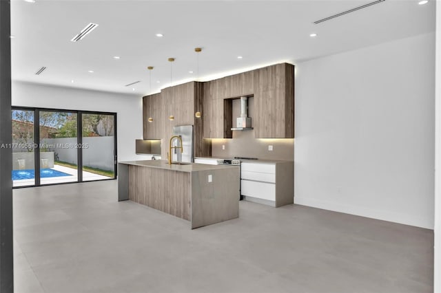 kitchen featuring visible vents, wall chimney exhaust hood, modern cabinets, a sink, and stainless steel appliances