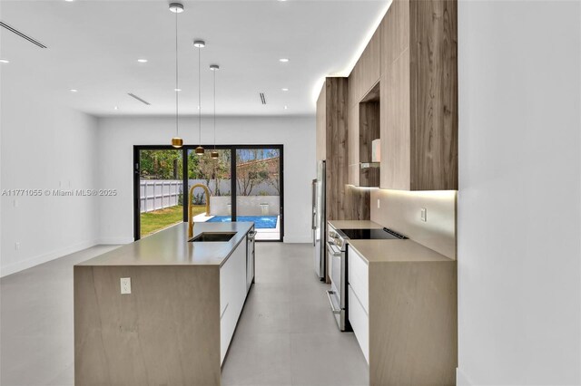 kitchen with a kitchen island with sink, a sink, modern cabinets, and stainless steel appliances