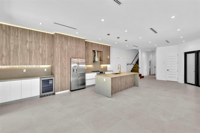 kitchen with modern cabinets, a sink, wine cooler, a center island with sink, and stainless steel appliances