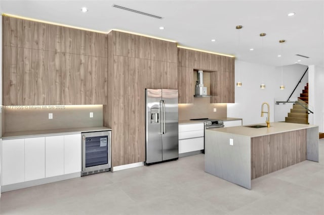 kitchen with an island with sink, modern cabinets, appliances with stainless steel finishes, a sink, and wine cooler