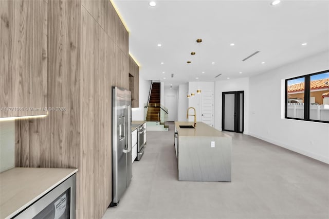 kitchen featuring an island with sink, a sink, modern cabinets, and recessed lighting
