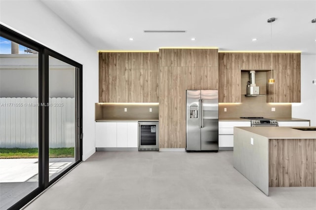 kitchen featuring modern cabinets, beverage cooler, light countertops, stainless steel appliances, and finished concrete floors