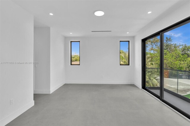 unfurnished room featuring finished concrete flooring, baseboards, and recessed lighting