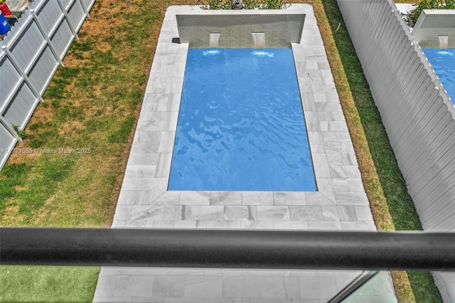 view of swimming pool with fence and a lawn