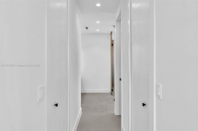 corridor featuring recessed lighting, finished concrete flooring, and baseboards
