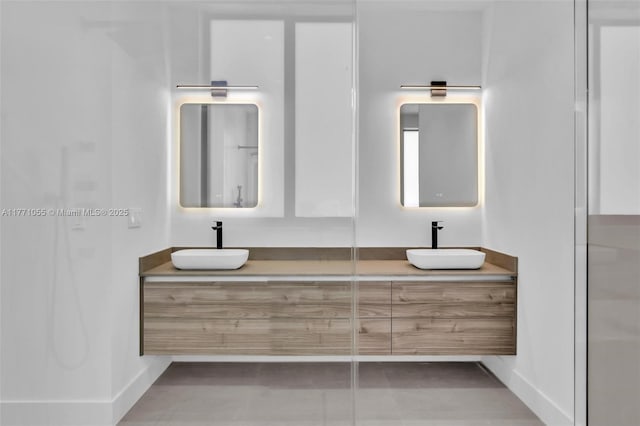 bathroom featuring a sink, baseboards, and double vanity