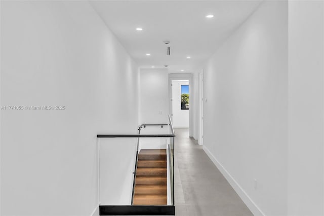hall featuring finished concrete floors, baseboards, and recessed lighting