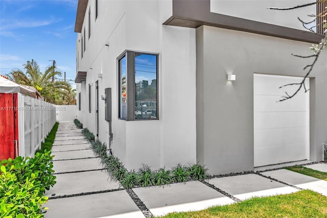 view of property exterior with stucco siding and fence