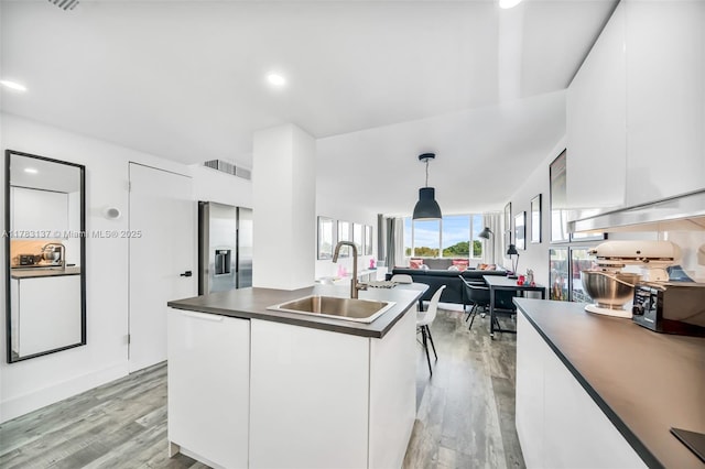8233 Harding Ave Unit 607, Miami Beach, FL 33141 - kitchen featuring stainless steel fridge, dark countertops, light wood finished floors, modern cabinets, and white cabinets