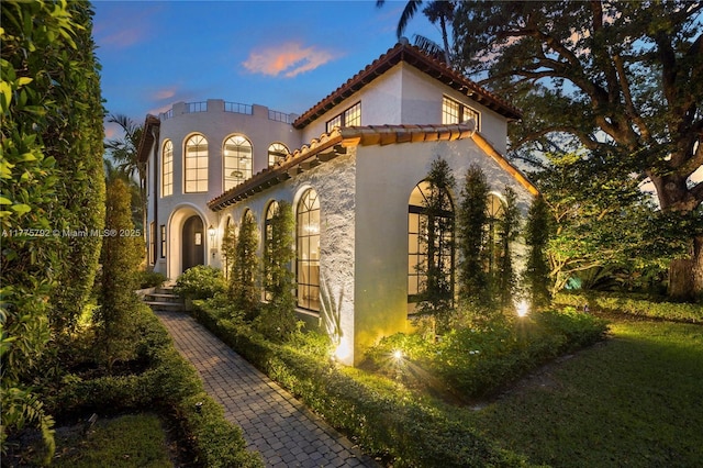 view of side of property with a tiled roof and stucco siding