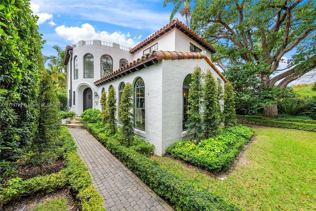 view of property exterior with a tile roof, a lawn, and stucco siding