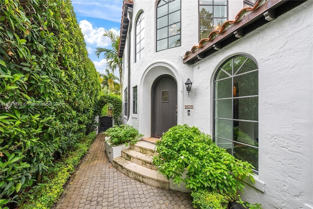 entrance to property featuring a tiled roof and stucco siding