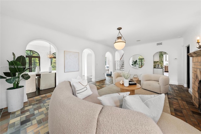living room featuring arched walkways, plenty of natural light, and a brick fireplace