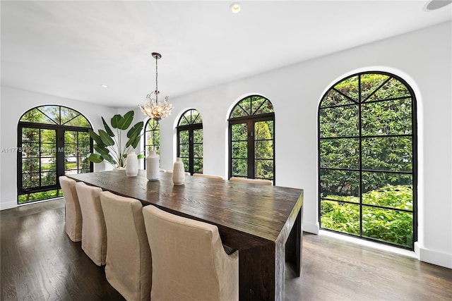 dining area with dark wood-type flooring, baseboards, and an inviting chandelier