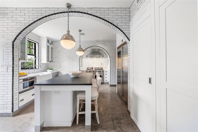 kitchen featuring a sink, a breakfast bar, high quality appliances, white cabinetry, and a kitchen island