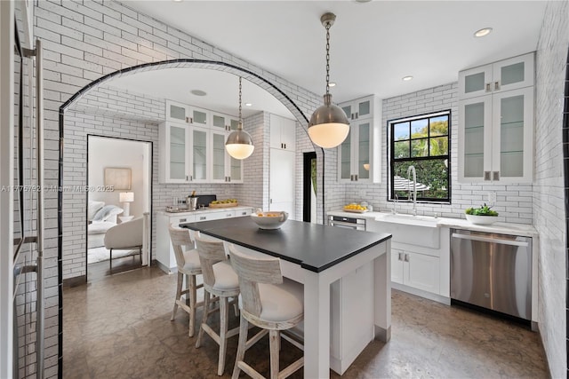 kitchen with a center island, backsplash, white cabinets, a kitchen bar, and dishwasher