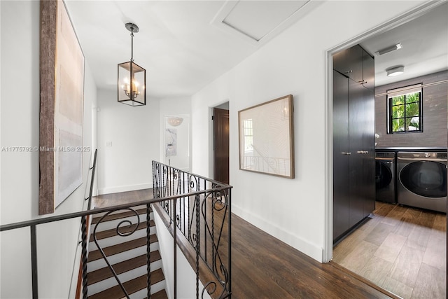 hallway with visible vents, wood finished floors, an upstairs landing, baseboards, and washing machine and dryer