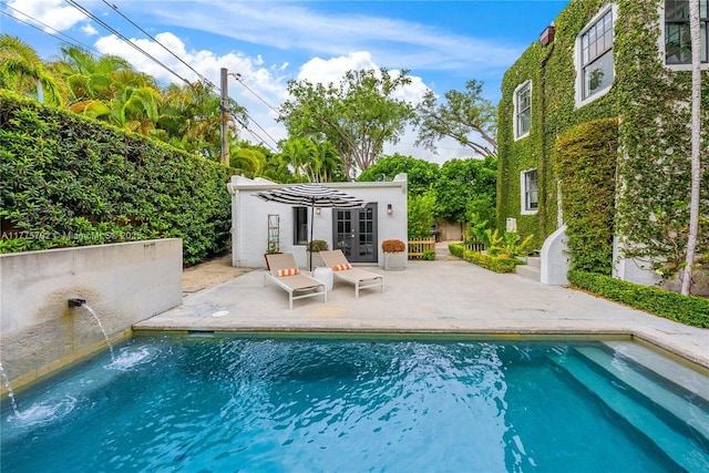 pool with an exterior structure, a patio area, french doors, and an outbuilding