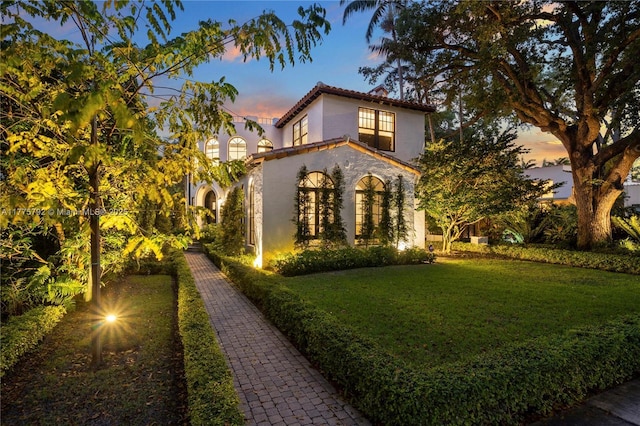 exterior space with a yard, stucco siding, and a tile roof