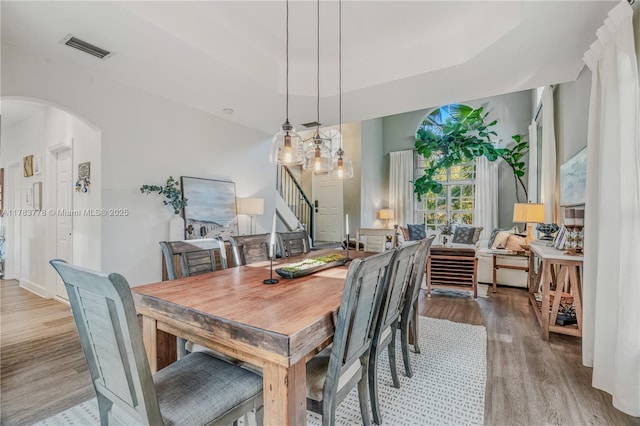 dining area featuring visible vents, wood finished floors, arched walkways, and stairway