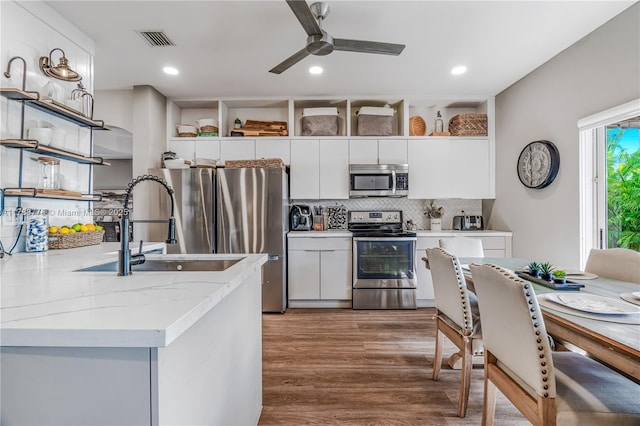 kitchen with stainless steel appliances, visible vents, wood finished floors, ceiling fan, and open shelves