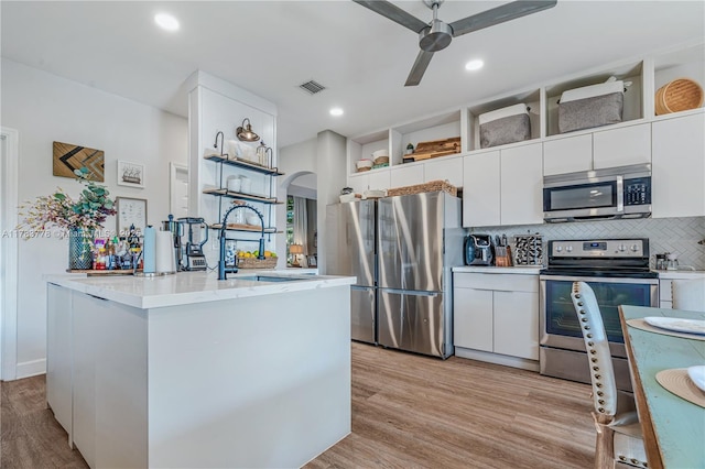 kitchen featuring a ceiling fan, open shelves, arched walkways, stainless steel appliances, and white cabinetry