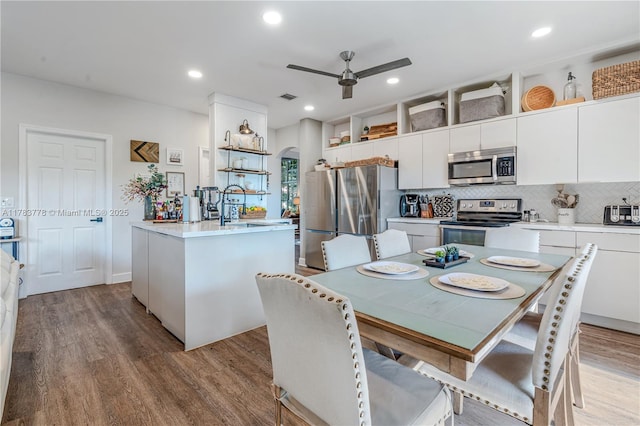 kitchen with ceiling fan, wood finished floors, arched walkways, and appliances with stainless steel finishes