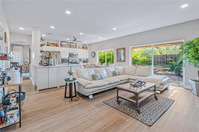 living area featuring light wood-type flooring, arched walkways, recessed lighting, and ceiling fan