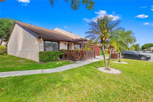 view of front of house featuring fence, a front yard, and stucco siding