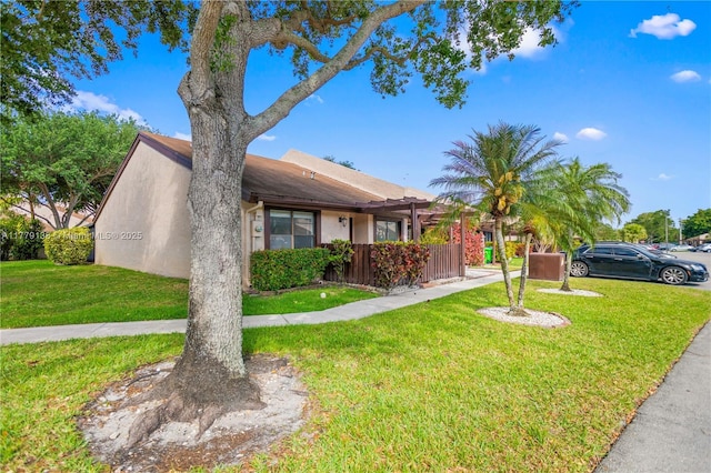 view of front of house featuring fence, a front yard, and stucco siding