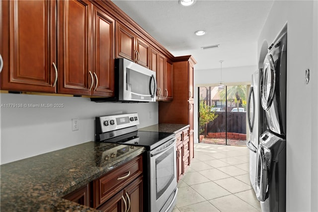 kitchen featuring stacked washer / drying machine, visible vents, light tile patterned flooring, pendant lighting, and appliances with stainless steel finishes