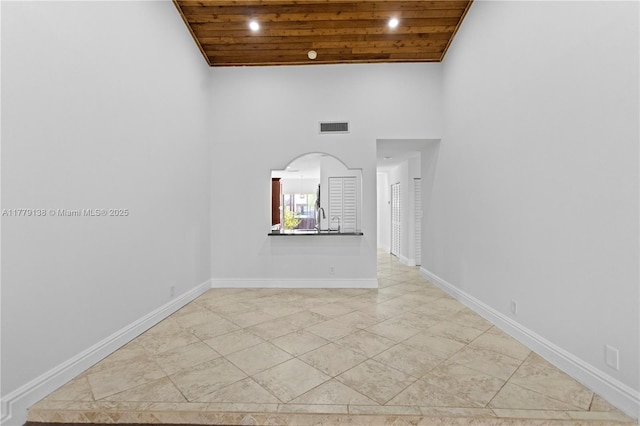 spare room with high vaulted ceiling, arched walkways, wooden ceiling, baseboards, and visible vents
